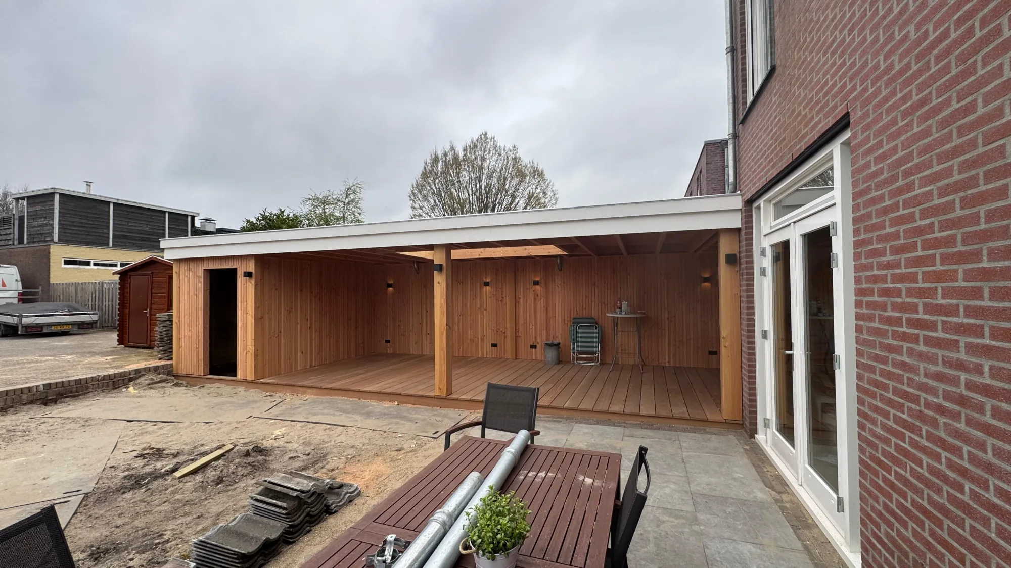 Overkapping in aanbouw met verlichting in de houten wanden